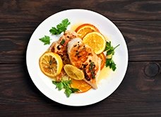 Grilled chicken breast with orange sauce on wooden background, top view